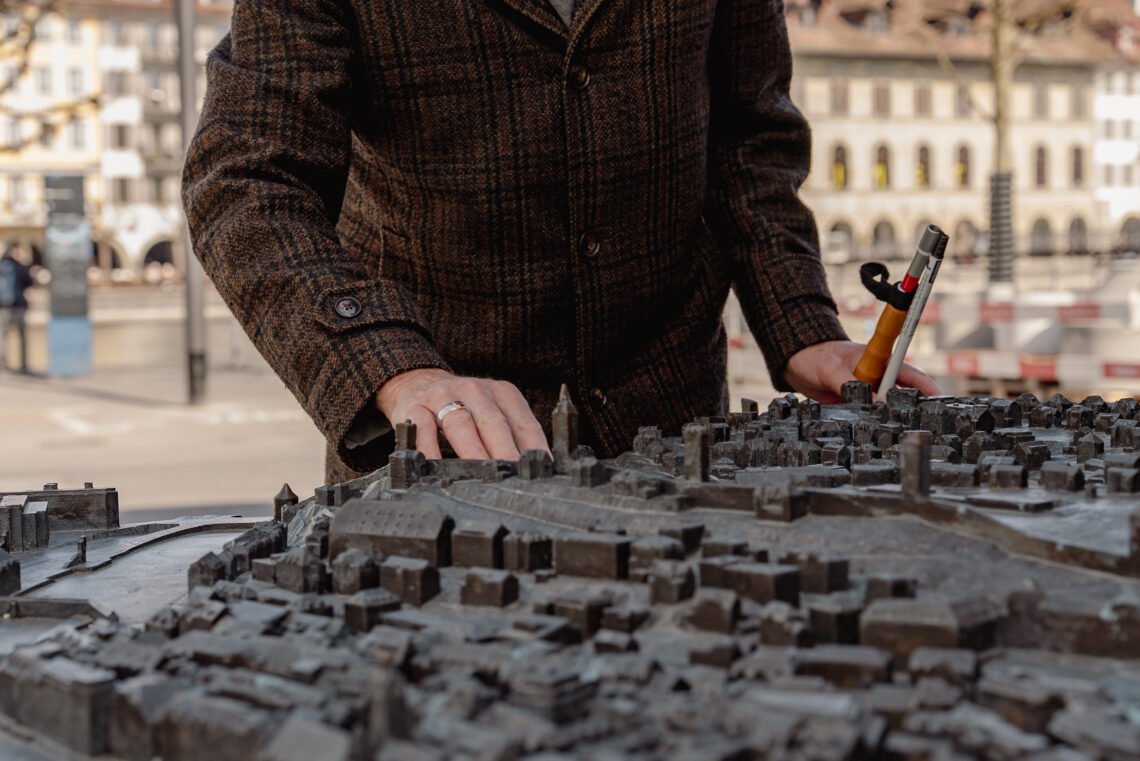 Eine blinde Person ertastet das Bronze Relief von Luzern - eine Nachbildung der Stadt mit den einzelnen Gebäuden, Brücken und Gewässer aus Bronze.